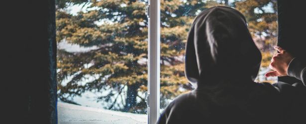 A person looking out a window thoughtfully.